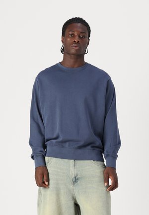 Sweatshirt bleu marine avec un col rond, des manches longues et des poignets et un ourlet côtelés. Associe avec un denim clair à coupe ample.