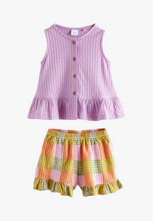 Mouwloze lavendelkleurige top met knopen en ruches aan de zoom, gecombineerd met oranje, groene en roze geruite short met elastische taille en gerimpelde randen.