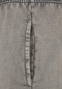 Grå sweatpants med en glat tekstur og en sidelomme. Elastikken i taljen har en samlet finish for komfort og fleksibilitet.