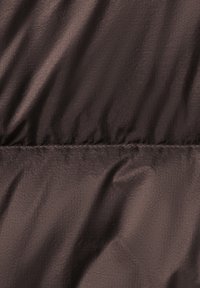 Tissu léger marron foncé avec une texture lisse et un léger éclat. La surface est légèrement froissée avec une couture qui court horizontalement.