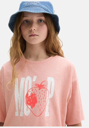 Junge Person mit langem Haar trägt einen blauen Marc O'Polo Fischerhut und ein rosa T-Shirt mit großem weißen und roten Erdbeermotiv.
