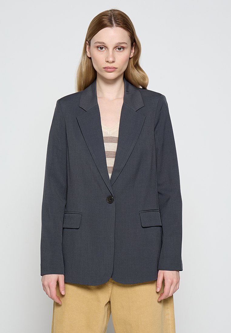 Blazer gris oscuro con solapas estructuradas, cierre de un solo botón, dos bolsillos frontales y corte ajustado, fabricado en una tela suave.