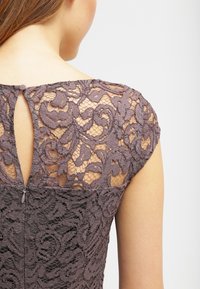 Robe en dentelle à manches courtes de couleur mauve atténuée, présentant des motifs floraux complexes et une fermeture à l'arrière avec une ouverture en forme de goutte.