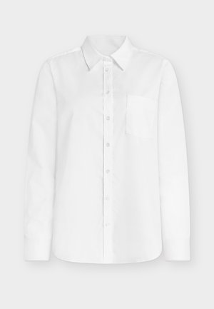 Biela košeľa s dlhým rukávom z bavlny, s výrazným špicatým golierom, zapínaním na gombíky po celej dĺžke a ľavým náprsným vreckom. Hladká textúra.