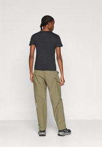 Μαύρο κοντομάνικο μπλουζάκι συνδυασμένο με χακί παντελόνι cargo. Το παντελόνι έχει πλαϊνές τσέπες και λογότυπο· τα παπούτσια είναι σκούρο γκρι με ρίγες.