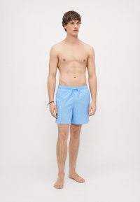 Jasnoniebieskie szorty kąpielowe wykonane z materiału szybkoschnącego, z elastycznym pasem i sznurkiem do regulacji, o gładkiej fakturze.
