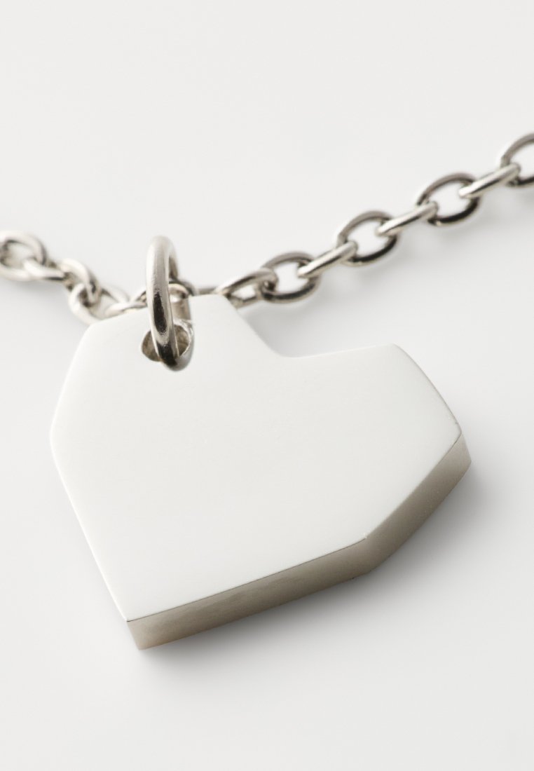 Silberner herzförmiger Anhänger mit einer glatten, polierten Oberfläche, ausgestattet mit einer oberen Schlaufe zur Befestigung an einer Kette. Geometrische Form mit leichter Dimension.