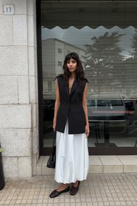 Must mustrinna mustris, millel on terav krae, kantud laia valge maxi seelikuga. Täiendatud mustade madalate kingade ja väikese musta kotiga.