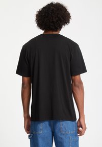 Svart bomull T-skjorte med korte ermer, med en klassisk rund hals. Brukt med lyseblå denim cargo bukser.
