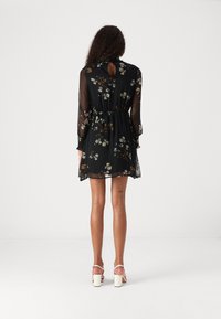 Rochie neagră cu imprimeu floral, material transparent, mâneci lungi, talie elastică, spate cu decupaj în formă de cheie și fusta vaporoasă care se termină la jumătatea coapsei.