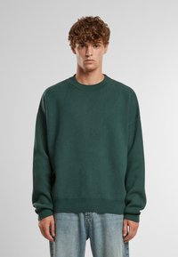 Grüner Pullover mit geripptem Rundhalsausschnitt und langen Ärmeln, aus einem weichen Strickstoff gefertigt. Verfügt über überschnittene Schultern und eine lockere Passform.