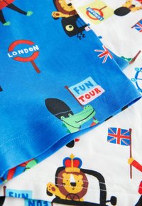 Två mönstrade tygstycken: ett i blått med tecknade djur och ikoner från London, det andra i vitt med färgglada illustrationer av landmärken.