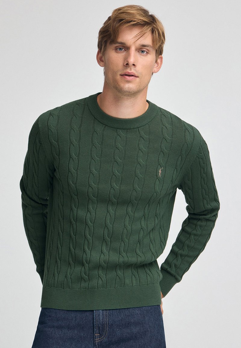 Grüner Pullover mit Zopfmuster, rundem Ausschnitt sowie gerippten Bündchen an Ärmeln und Saum. Verfügt über ein kleines Logo auf der Brust. Weiche Strickstruktur.