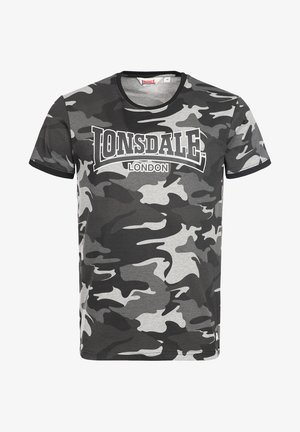 Pelēkā kamuflāžas T-kreklā, kas izgatavots no kokvilnas. Tam ir apaļais kakls, īsās piedurknes un izteiksmīgs balts "Lonsdale London" logo pa krūtīm.