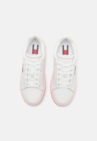 Weiße niedrige Sneakers aus glattem Leder mit pinkfarbenen Gummisohlen und dekorativen roten und blauen Logopunkten.