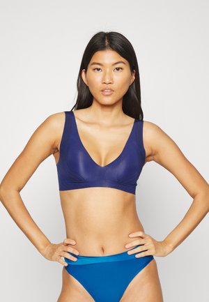 Marineblauwe sportbeha met een diepe V-hals, brede banden en getextureerde lijnen. Gecombineerd met een effen blauwe bikinibroek. Glad materiaal.