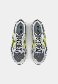 Chaussures de sport pour hommes avec une tige en maille grise, des accents jaunes et des semelles texturées ; elles possèdent un laçage et un logo sur la languette.