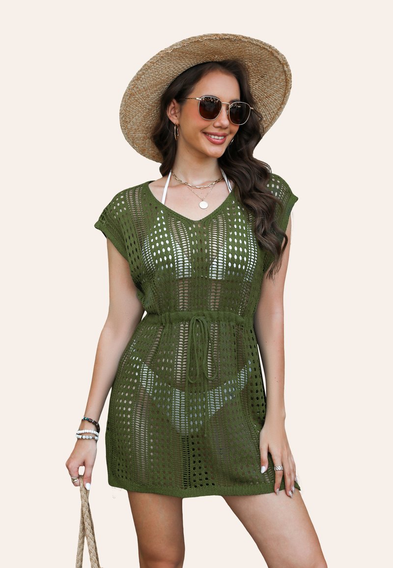 Abito coprente in crochet verde oliva, maniche corte, scollatura a V, vita con cordoncino, con motivi a maglia aperta e sovrapposto a un costume da bagno.