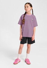 Lila gestreiftes T-Shirt mit kurzen Ärmeln, kombiniert mit schwarzen Shorts. Rosa Sneakers, weiße Kniestrümpfe. Einfaches, lässiges Design.