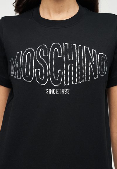 Μαύρο βαμβακερό T-shirt με την ένδειξη «MOSCHINO» σε ασημί στρας. Λαιμόκοψη crew, κοντά μανίκια, μαλακή υφή και άνετη εφαρμογή.