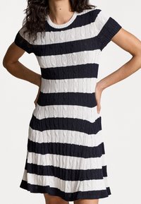 Stickad klänning med horisontella marinblå och vita ränder, med ett texturerat kabelmönster, korta ärmar och en utsvängd nederdel.