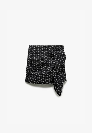 Czarna spódnica z tkaniny z białym wzorem kwiatowym, z detalem w postaci węzła z przodu i lekko teksturowaną powierzchnią, co podkreśla jej design.