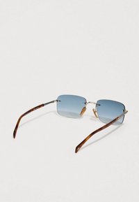 Bezčrne kvadratne sončna očala s modrim odtenkom, srebrnim nosnim mostičkom in rjavo želvovino tempeljema, prikazana od zgoraj na svetlem ozadju.