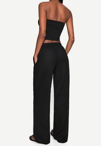 Black strapless top and wide-leg black pants, featuring a loose fit, soft texture, and side pockets. The design emphasizes comfort and ease.