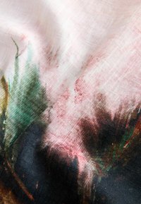 Tissu rose doux avec des motifs floraux abstraits verts et foncés, montrant une texture délicate et des plis légers.