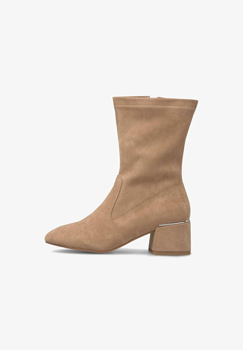 Botas de tobillo de ante beige con punta afilada y tacón bajo tipo bloque, con un acento metálico y detalles de costura en las costuras.