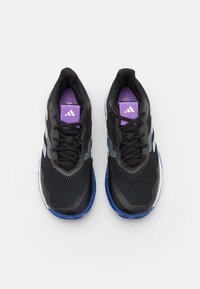 Černé sportovní boty s prodyšným svrškem, fialovými detaily a bílými pruhy. Modrá gumová podešev pro lepší přilnavost. Šněrování.