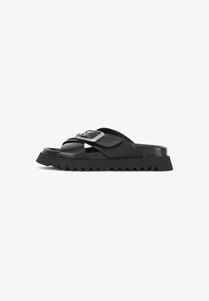 Black leather slide sandals with a wide cross-strap design, featuring a silver buckle accent and a textured, zigzag outsole.