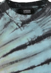 T-shirt tie-dye en nuances de bleu et noir, avec un col rond, des manches courtes, et un tissu en coton texturé. Étiquette visible à l'intérieur du col.