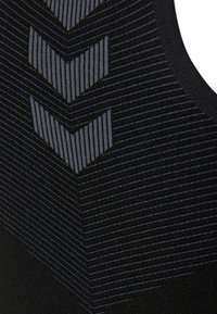Mustat urheilupaidat, joissa on tekstuuriset vaakasuorat raidat vaaleammassa harmaassa chevron-kuviossa. Valmistettu liukkaasta ja joustavasta kankaasta.