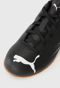 Zapato de fútbol negro con parte superior texturizada, cordones negros y un logo de Puma blanco. Cuenta con una suela de goma para tracción y durabilidad.