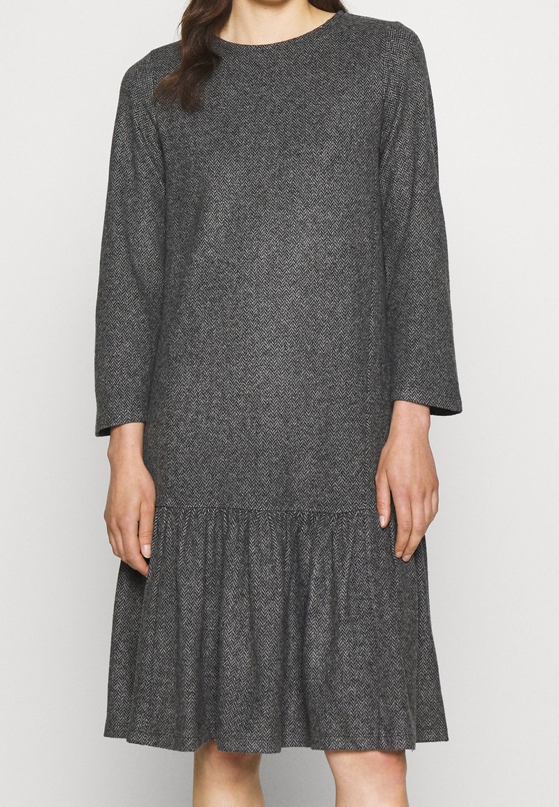 Robe en chevrons gris avec manches longues, encolure ronde et ourlet à volants. Fabriquée en tissu texturé, elle offre une coupe décontractée.