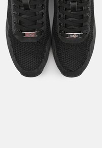 Svarta atletiska sneakers med en texturerad mesh-ovandel, rund tå, vadderad plös och platta snören, med metalliska logotypdetaljer.