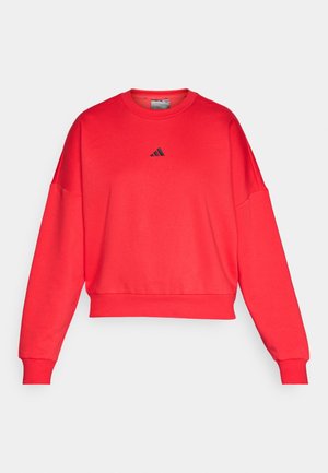 Felpa rossa corta con collo a giro e spalle scese. Presenta un piccolo logo Adidas nero sul petto. Tessuto morbido.