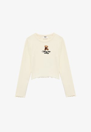 Cremefarbener Langarm-Crop-Top mit gewelltem Saum, versehen mit einem Bären-Graphic und dem schwarz gestickten Schriftzug "Always keep smiling". Strukturierter Rippstoff.