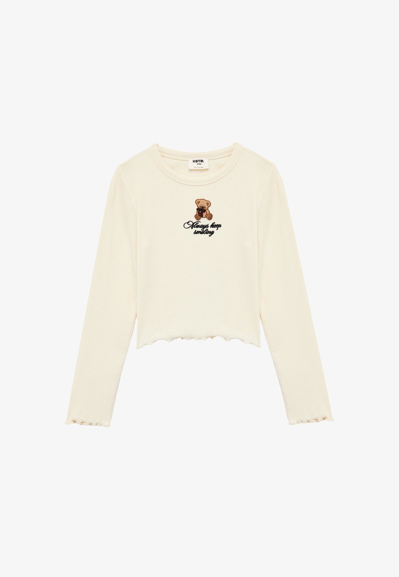 Cremefarbener Langarm-Crop-Top mit gewelltem Saum, versehen mit einem Bären-Graphic und dem schwarz gestickten Schriftzug "Always keep smiling". Strukturierter Rippstoff.