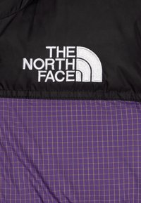 Crna i ljubičasta jakna s uzorkom mreže, prošivenom teksturom i izvezenim logotipom "The North Face" u bijeloj boji.