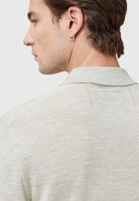 Lys grøn polo skjorte lavet af blødt stof, med strikket tekstur, kort krave og syninger på bagsiden.