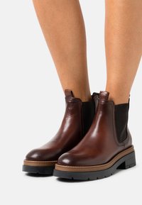 Bruna läder Chelsea-boots med svarta elastiska sidopaneler, rund tå, staplad sula och strukturerad sula för grepp.