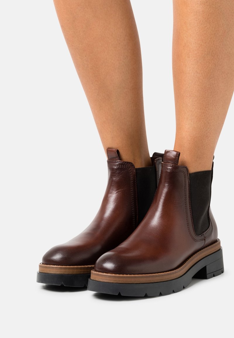 Bruna läder Chelsea-boots med svarta elastiska sidopaneler, rund tå, staplad sula och strukturerad sula för grepp.