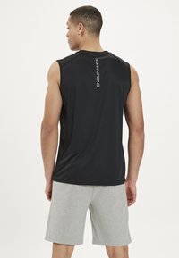 Sort ærmeløs træningsbluse med en glat tekstur, der har et lodret "ENDURANCE" logo på ryggen. Sammen med grå shorts.