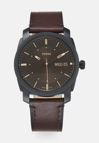 Fossil-Uhr mit schwarzem Zifferblatt, Datumsanzeige und braunem Lederarmband. Verfügt über eine strukturierte Lünette und goldene Akzente bei den Stundenmarkierungen und Zeigern.