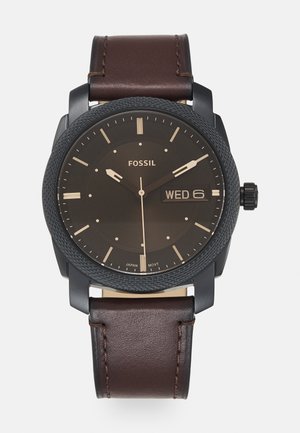 Fossil-Uhr mit schwarzem Zifferblatt, Datumsanzeige und braunem Lederarmband. Verfügt über eine strukturierte Lünette und goldene Akzente bei den Stundenmarkierungen und Zeigern.