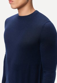 Marineblauer Strickpullover mit rundem Ausschnitt, aus weichem Stoff gefertigt, mit schmaler Passform und langen Ärmeln.