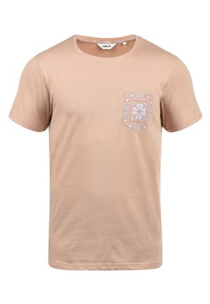 Camiseta de algodón beige con cuello redondo y mangas cortas. Presenta un bolsillo estampado en el lado izquierdo del pecho en azul y blanco.