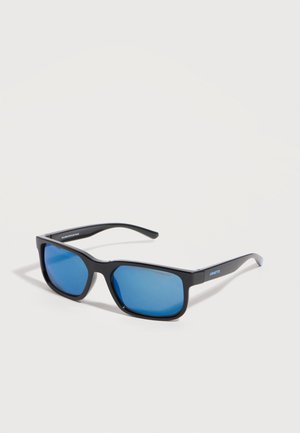 Schwarze rechteckige Sonnenbrille mit blau verspiegelt Gläsern, die auf einer hellen Oberfläche liegt, mit einem schlanken Rahmen und der Aufschrift "ARNETTE" am Bügel.
